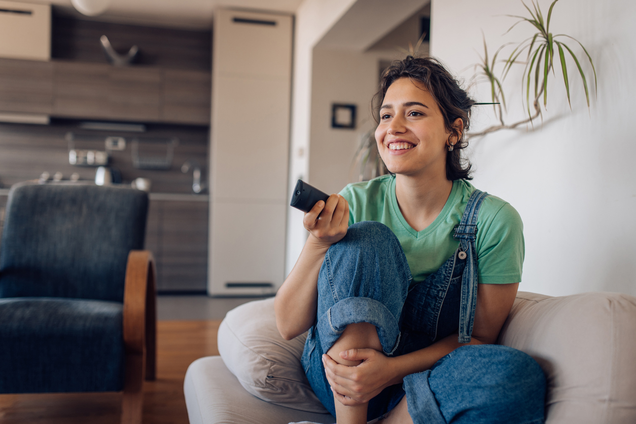 Young woman using tv remote control